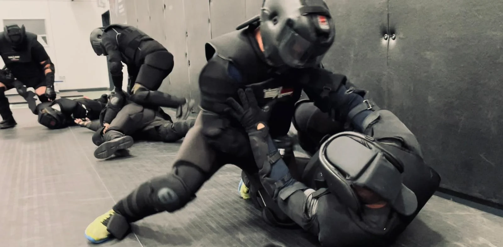 Two pairs of trainers in HIGH GEAR suits grappling on the mats